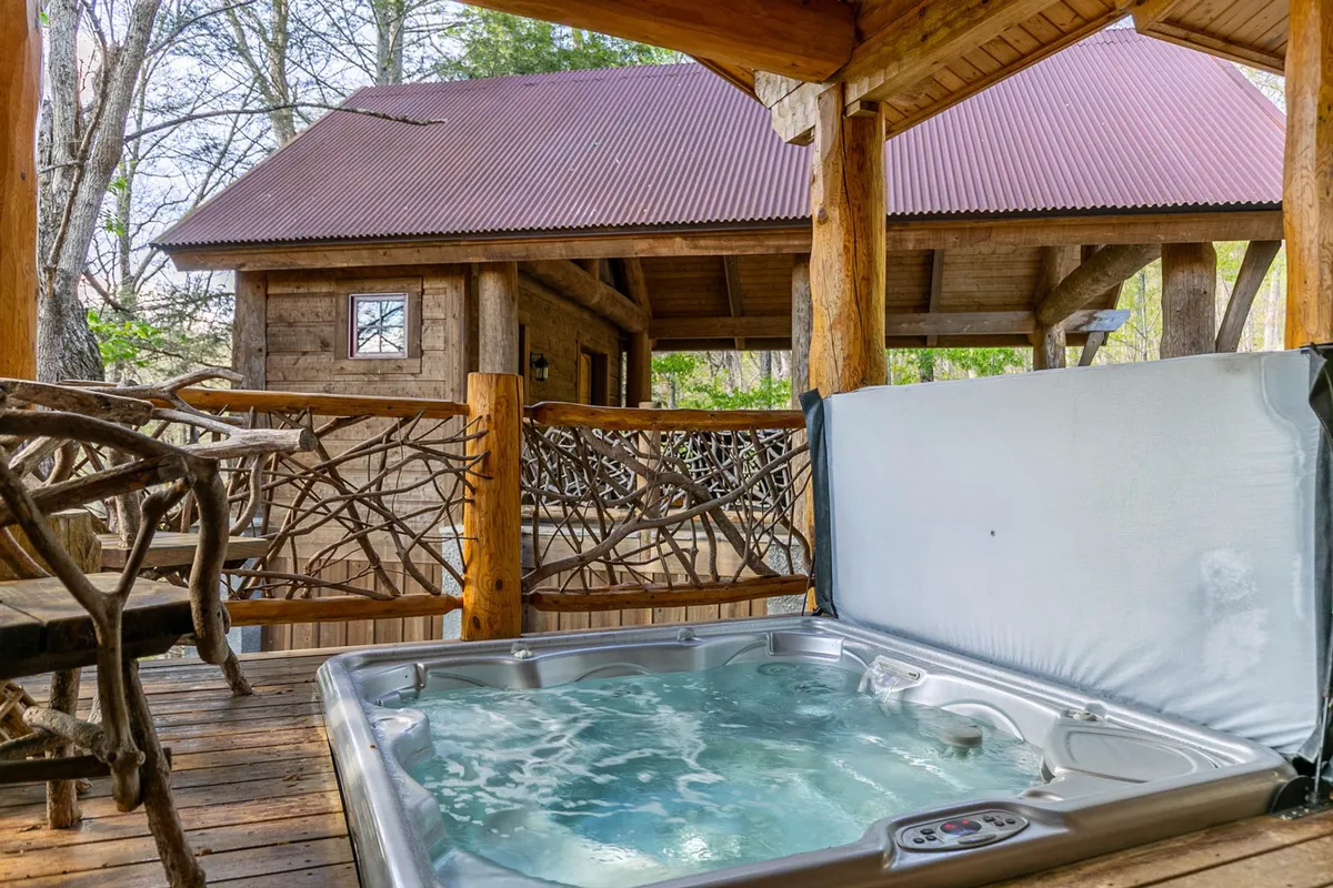 An inviting outdoor hot tub set against a wooden structure and natural surroundings. The scene is tranquil and hints at relaxation after a day of adventure, with trees and natural elements framing the deck area.