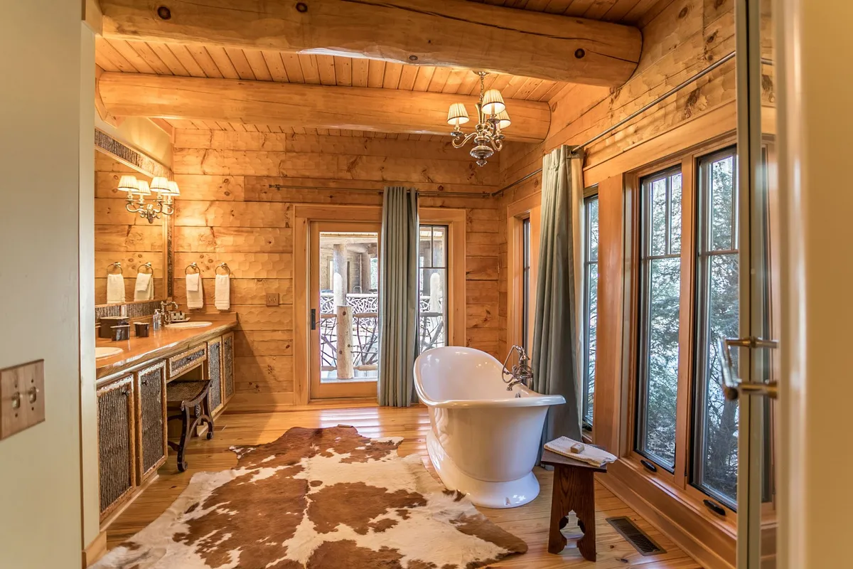 A luxurious bathroom with a freestanding soaking tub, an elegant vanity with dual mirrors, large windows offering natural light, and a sparkling chandelier. The setup evokes a spa-like atmosphere, perfect for unwinding after a day of adventure.