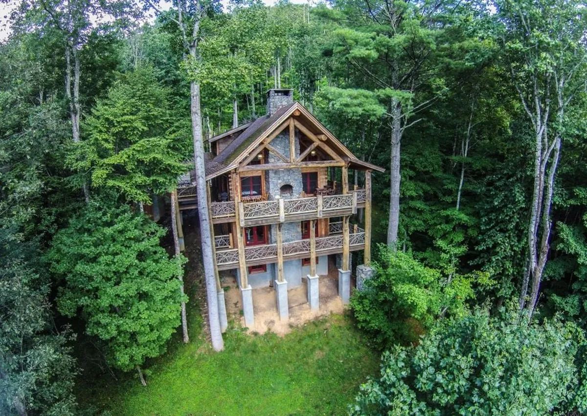 A broad view of the lodge with its detailed wooden and stone structure, multiple balconies with intricate railings, and a backdrop of towering trees. The image radiates tranquility and highlights outdoor spaces ideal for coffee breaks, team-building, or unwinding after a productive day.