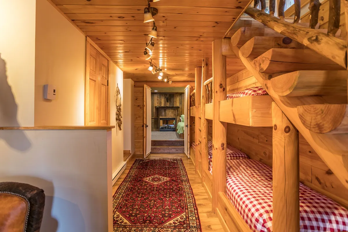 A cozy lower-level suite with built-in bunk beds, a wooden staircase, and a soft area rug. The design invites relaxation and play, making it ideal for children or guests seeking a private retreat after an active day.